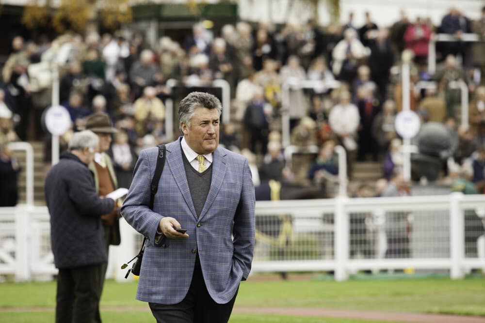 Trainer Paul Nicholls walking at Cheltenham Racecourse with the crowd in the background during the National Hunt season.